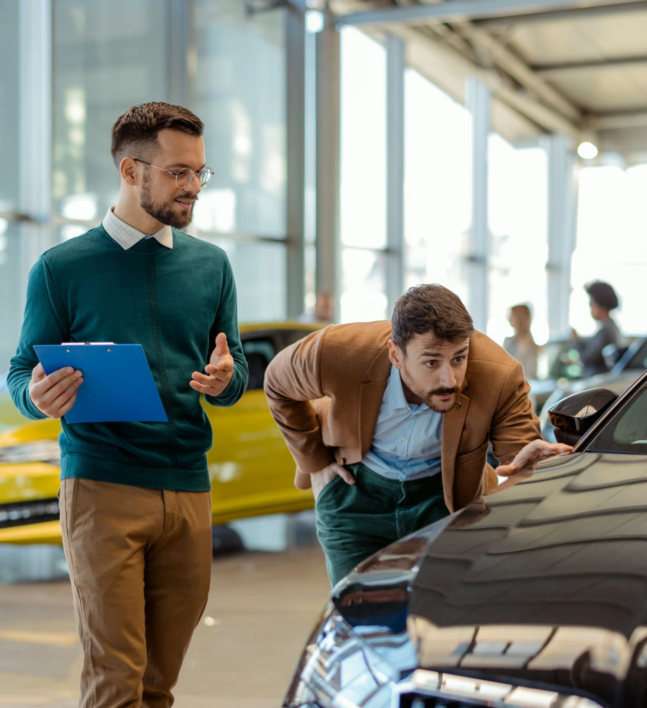 Customer examining vehicle while salesman assists